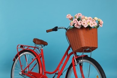 Photo of Bicycle with basket of beautiful flowers on light blue background