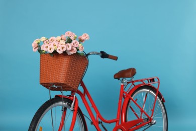 Photo of Bicycle with basket of beautiful flowers on light blue background