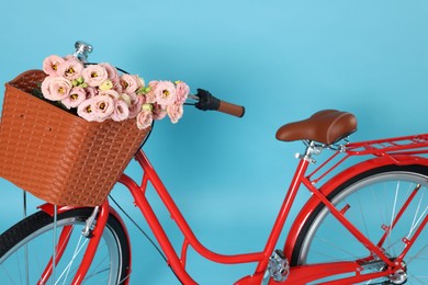 Photo of Bicycle with basket of beautiful flowers on light blue background