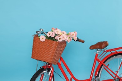 Photo of Bicycle with basket of beautiful flowers on light blue background