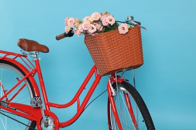 Photo of Bicycle with basket of beautiful flowers on light blue background