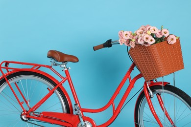 Photo of Bicycle with basket of beautiful flowers on light blue background