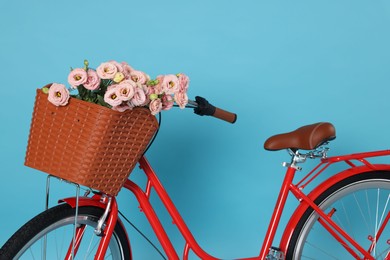 Photo of Bicycle with basket of beautiful flowers on light blue background