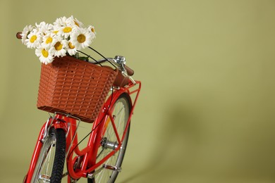 Photo of Bicycle with basket of beautiful flowers on green background. Space for text