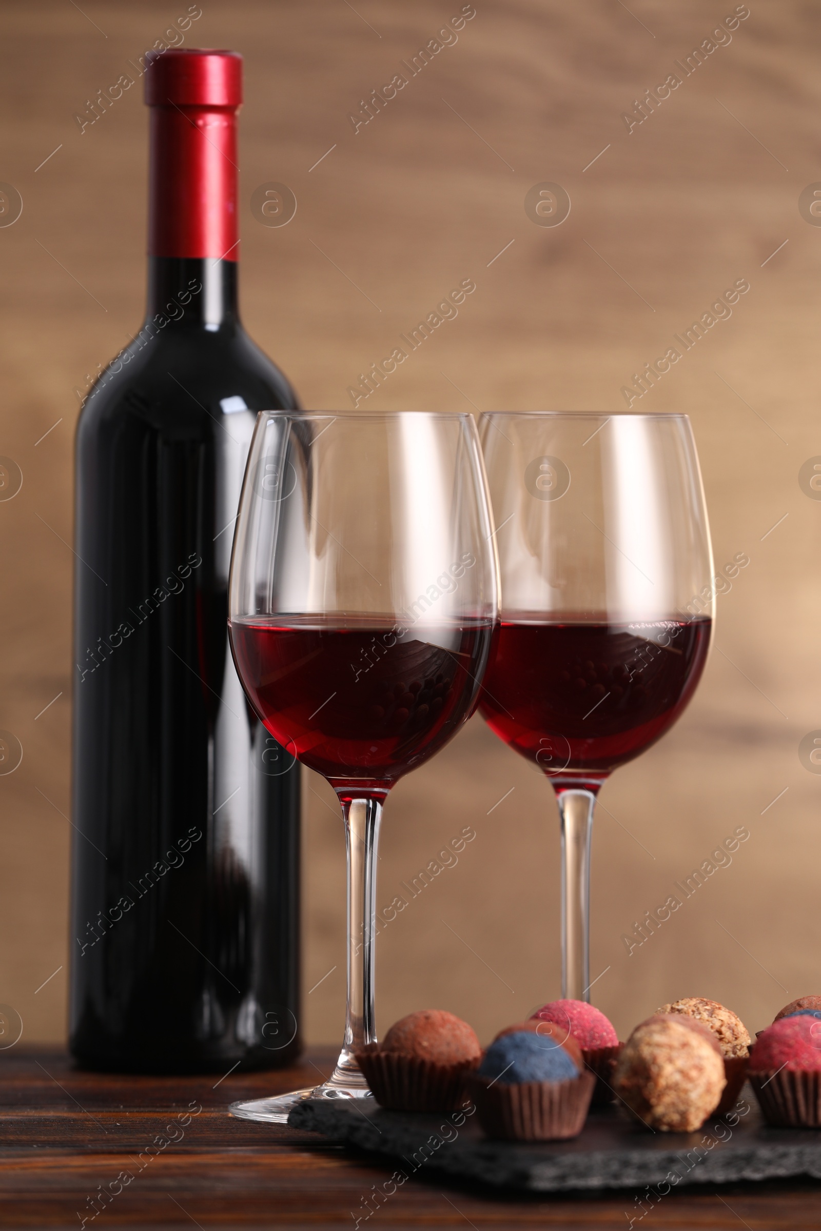 Photo of Delicious truffle bonbons and wine on wooden table