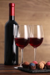 Photo of Delicious truffle bonbons and wine on wooden table