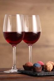 Photo of Delicious truffle bonbons and wine on wooden table
