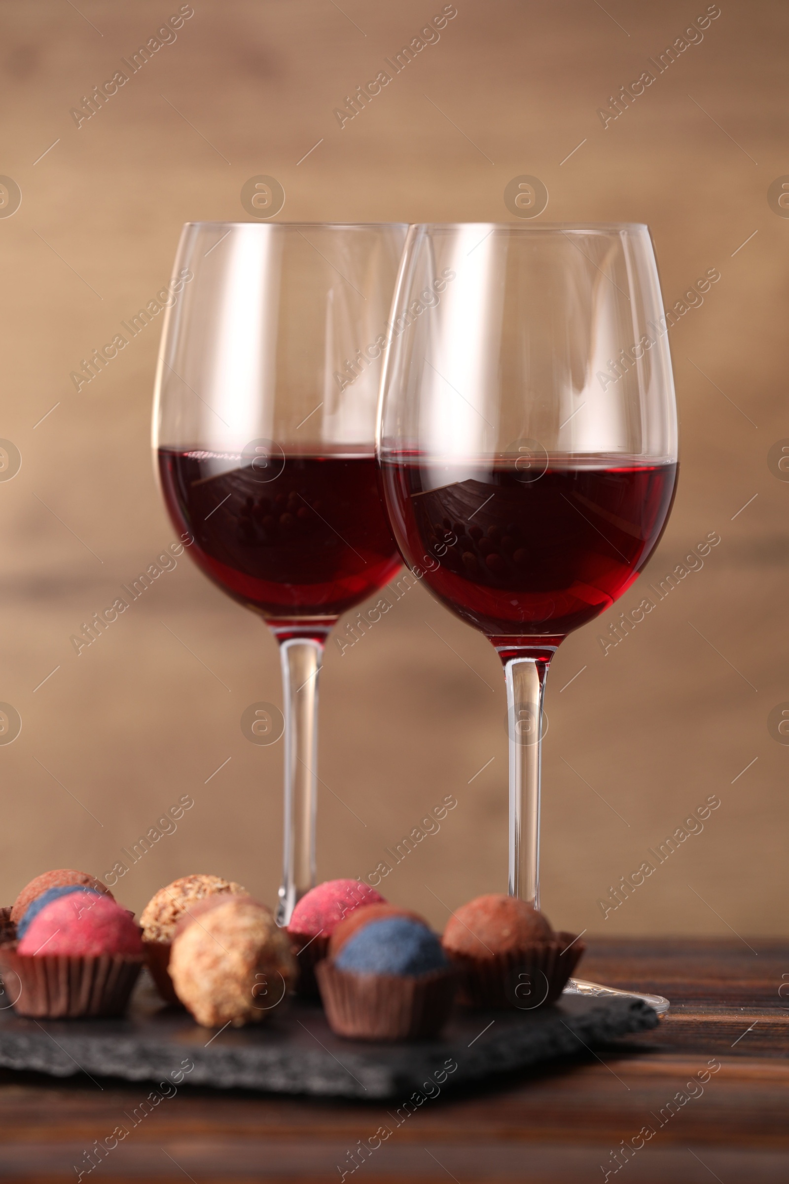 Delicious truffle bonbons and wine on wooden table Photo of Delicious truffle bonbons and wine on wooden table