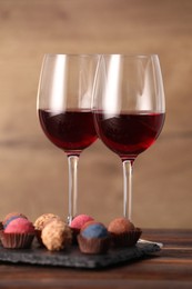 Photo of Delicious truffle bonbons and wine on wooden table
