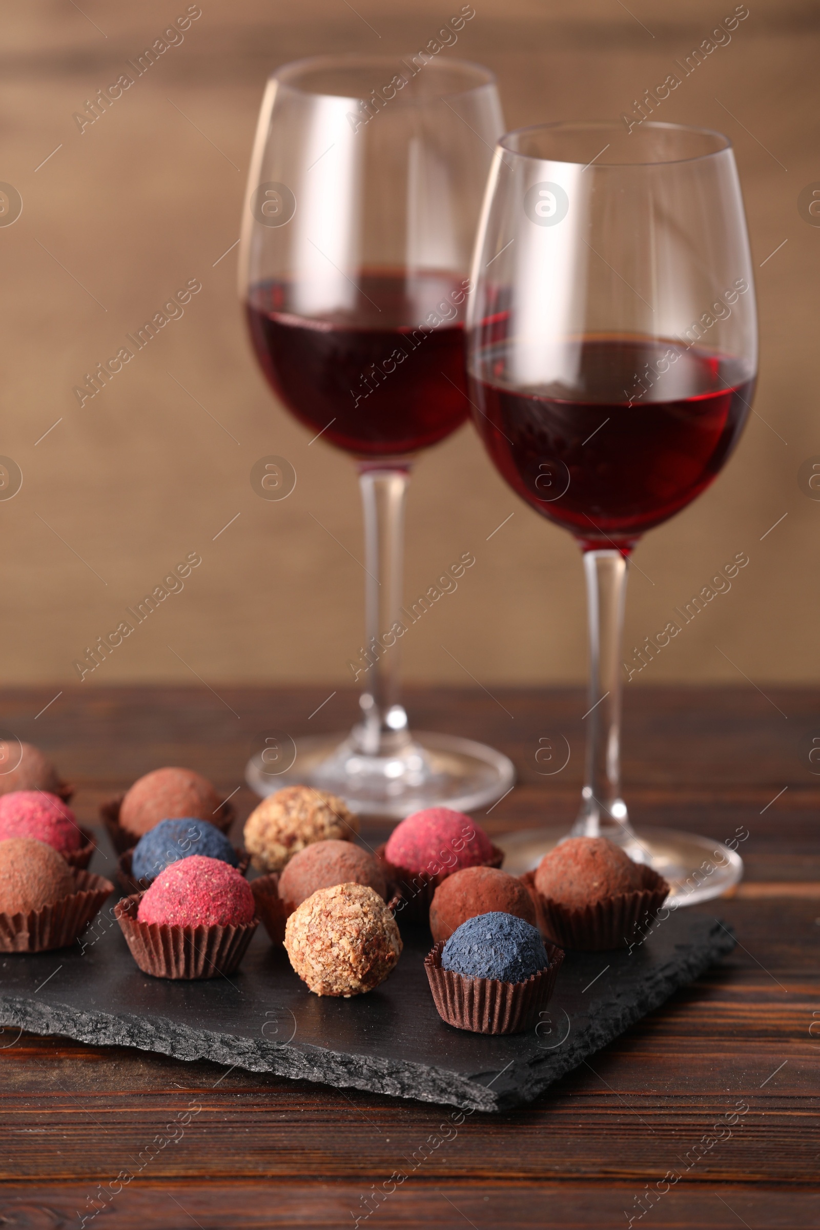 Photo of Delicious truffle bonbons and wine on wooden table
