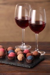 Photo of Delicious truffle bonbons and wine on wooden table