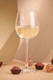 Photo of Delicious truffle bonbons and wine on beige background