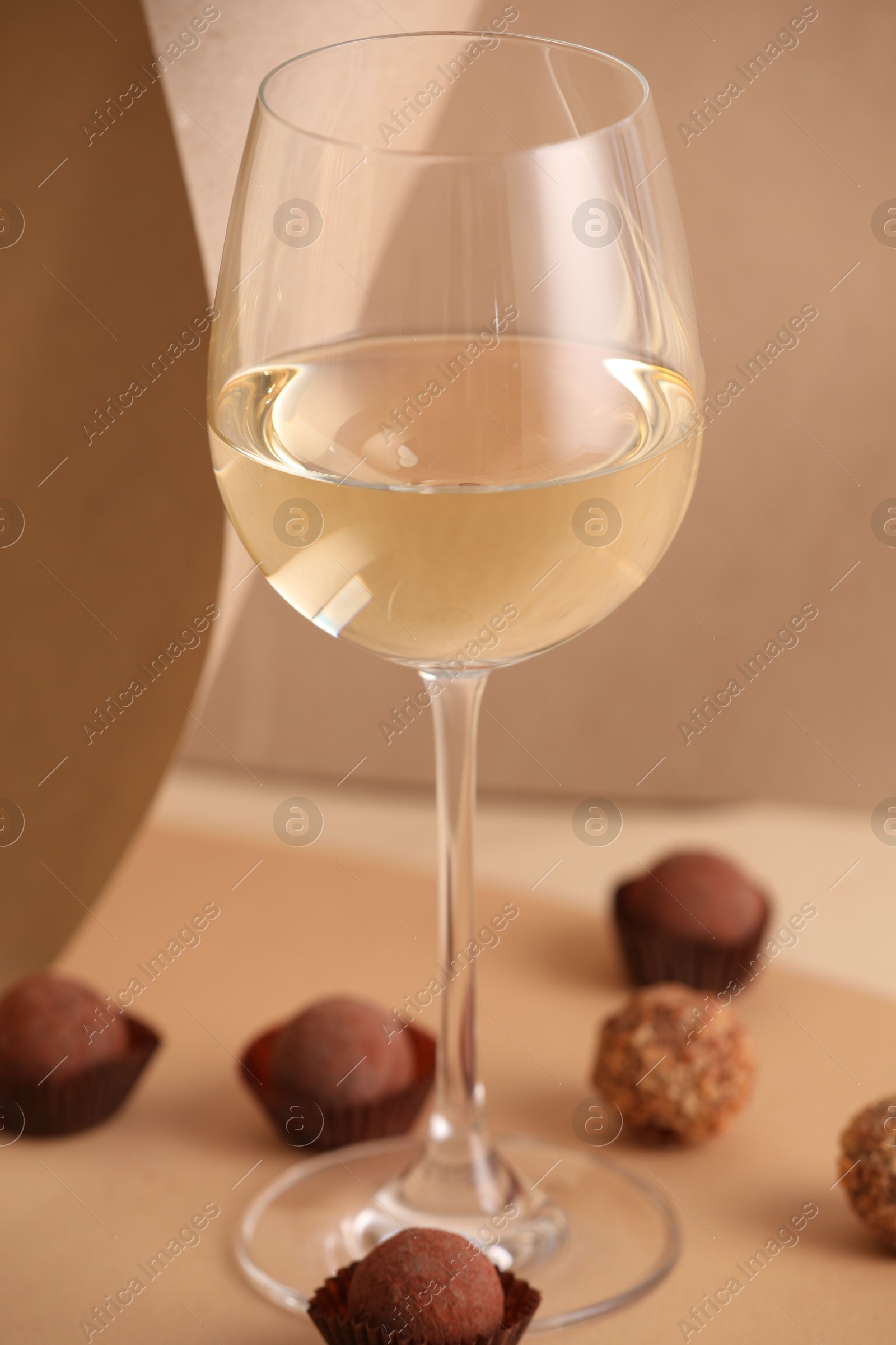 Photo of Delicious truffle bonbons and wine on beige background