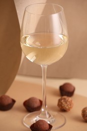 Photo of Delicious truffle bonbons and wine on beige background
