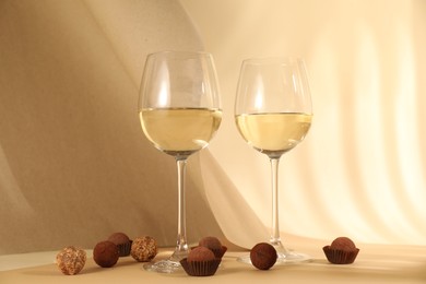 Photo of Delicious truffle bonbons and wine on beige background