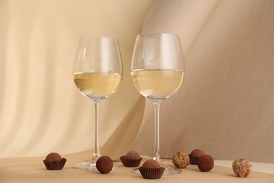 Photo of Delicious truffle bonbons and wine on beige background