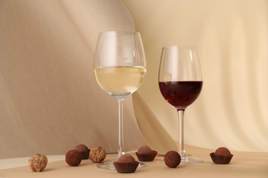 Photo of Delicious truffle bonbons and wine on beige background