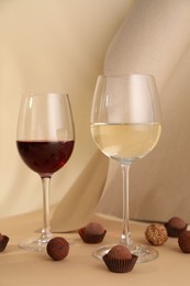 Photo of Delicious truffle bonbons and wine on beige background