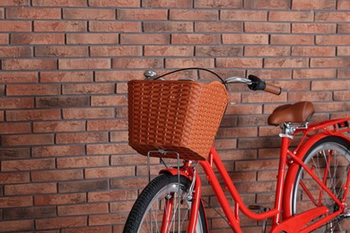 Photo of Red bicycle with basket near brick wall indoors, closeup. Space for text
