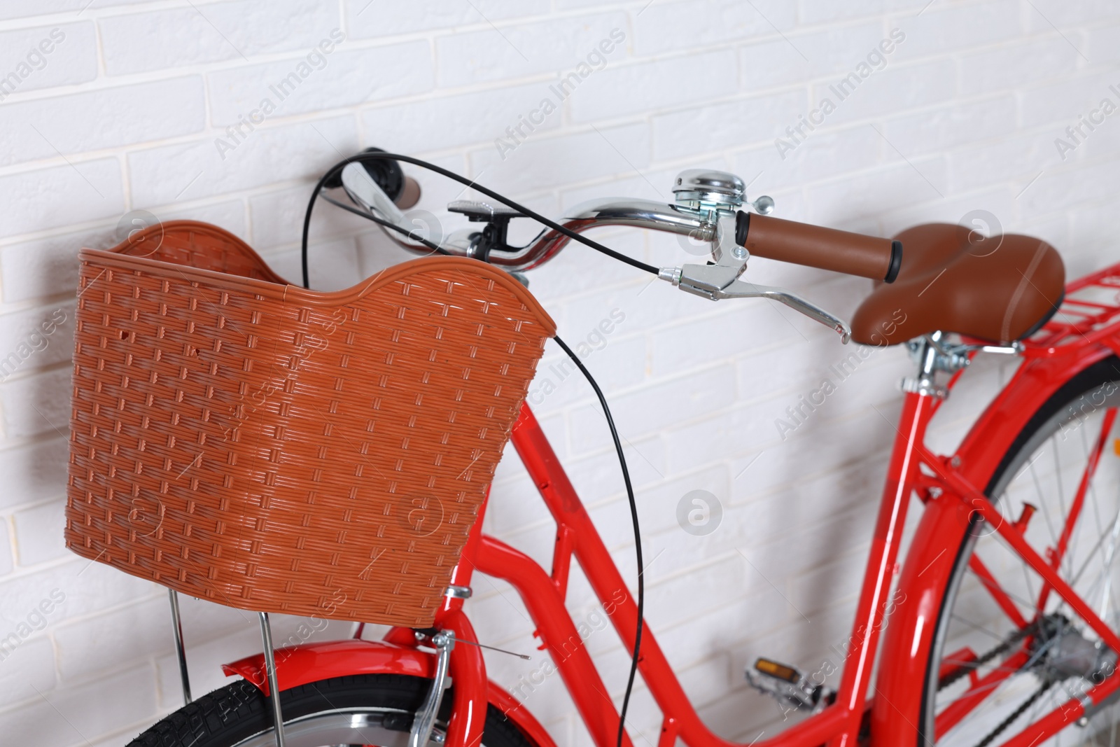 Red bicycle with basket near white brick wall indoors, closeup Photo of Red bicycle with basket near white brick wall indoors, closeup
