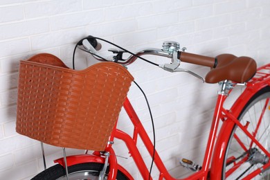 Photo of Red bicycle with basket near white brick wall indoors, closeup