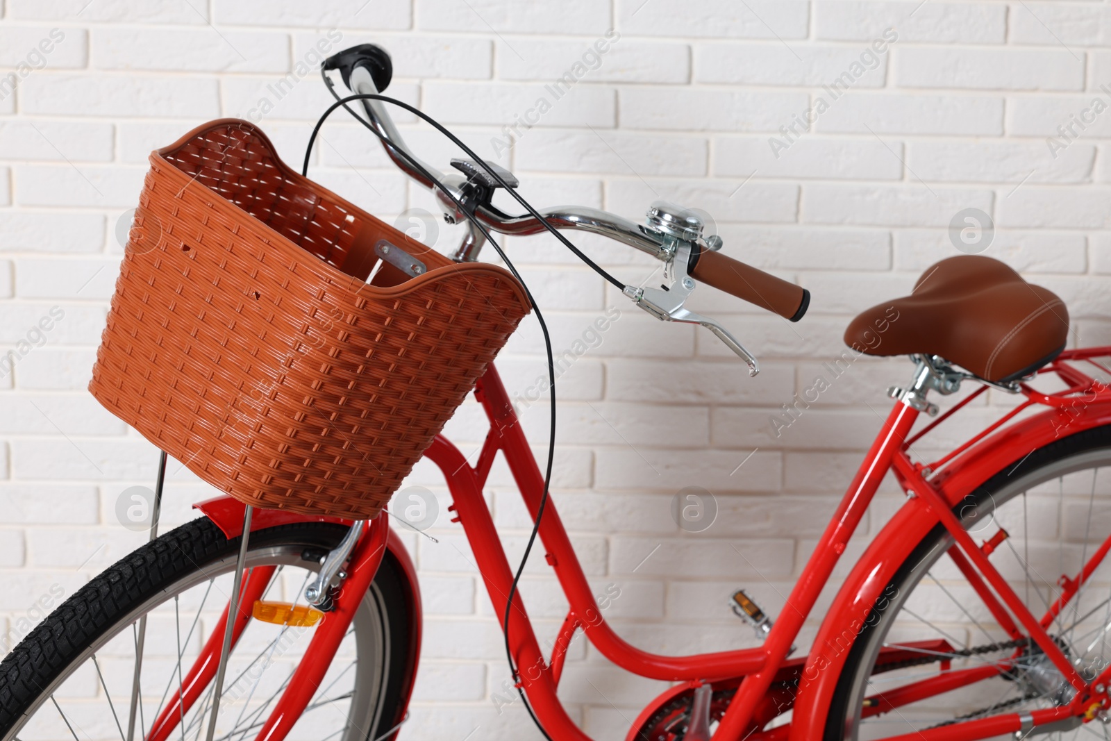 Red bicycle with basket near white brick wall indoors, closeup Photo of Red bicycle with basket near white brick wall indoors, closeup