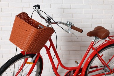 Photo of Red bicycle with basket near white brick wall indoors, closeup