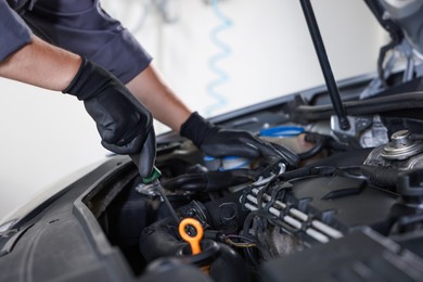 Photo of Auto parts. Professional mechanic with screwdriver fixing car indoors, closeup
