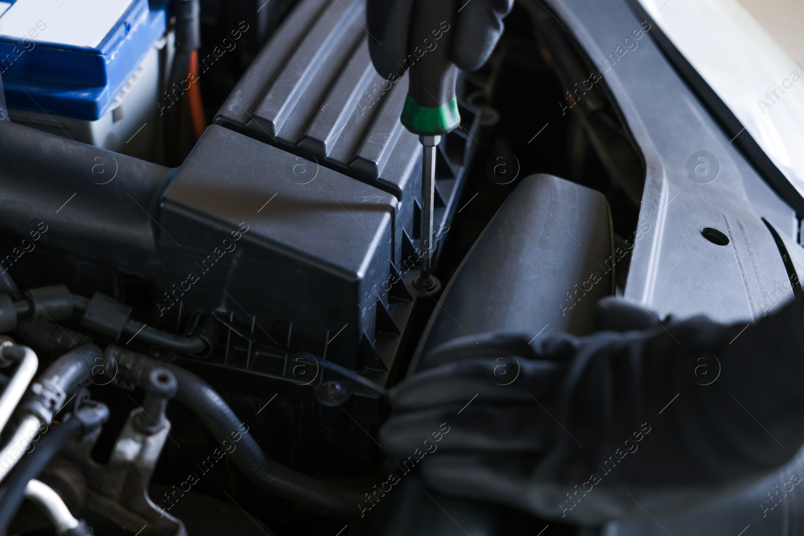 Auto parts. Professional mechanic with screwdriver fixing car indoors, closeup Photo of Auto parts. Professional mechanic with screwdriver fixing car indoors, closeup