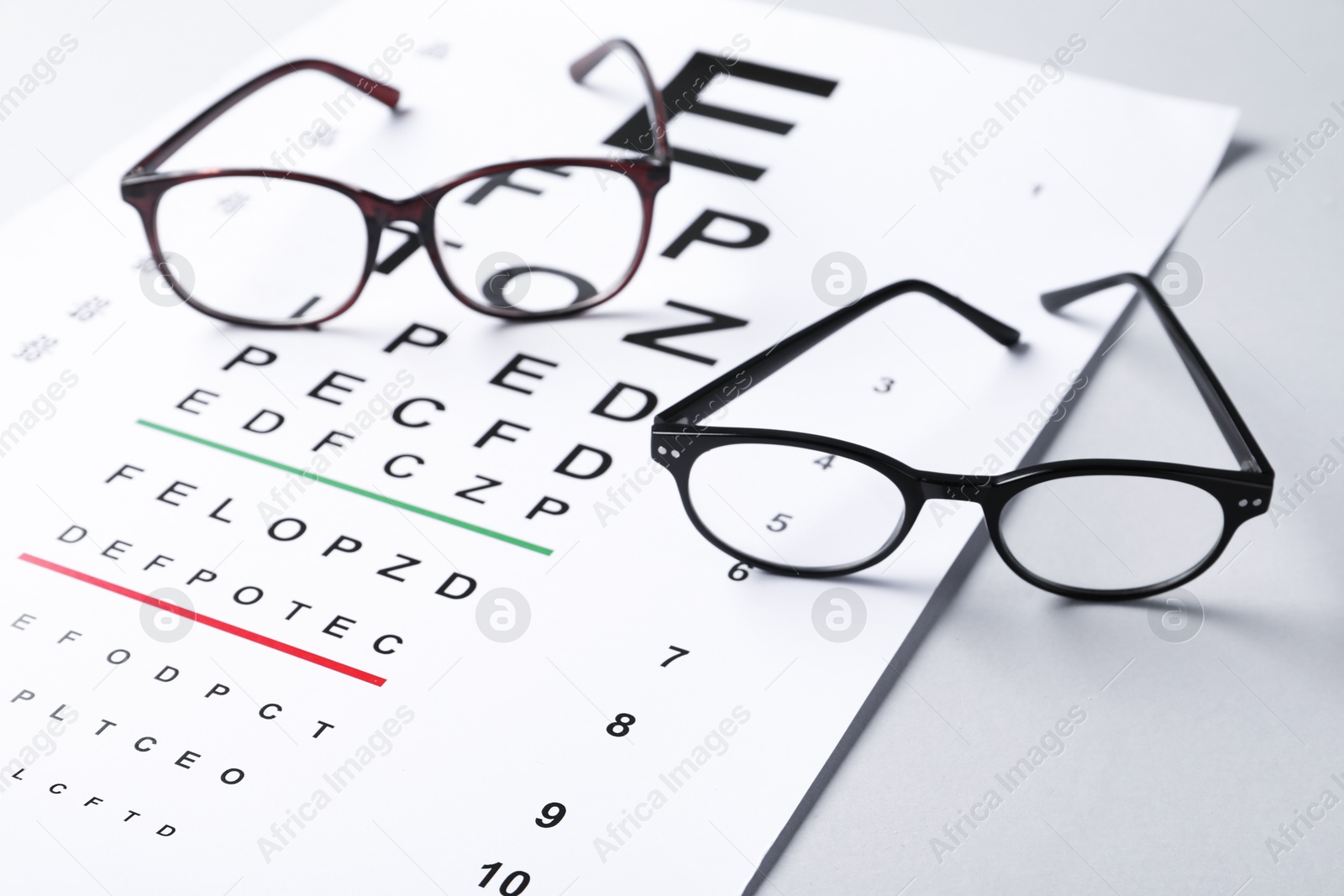 Vision test chart and glasses on light grey background, closeup Photo of Vision test chart and glasses on light grey background, closeup