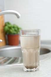 Photo of Glass with dirty water near sink indoors