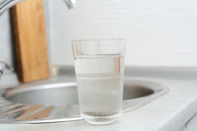 Photo of Glass with dirty water near sink indoors