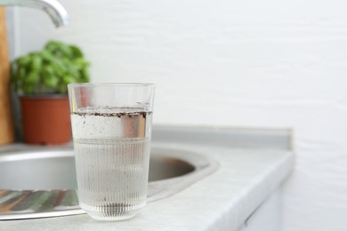 Photo of Glass with dirty water near sink indoors. Space for text