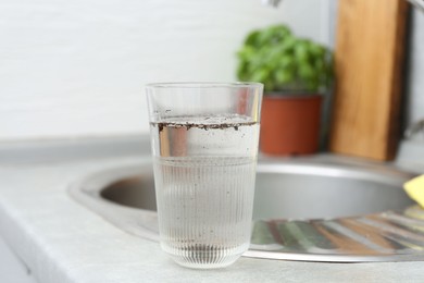 Photo of Glass with dirty water near sink indoors