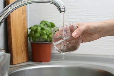 Photo of Woman filling glass with dirty tap water indoors, closeup