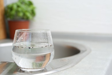 Photo of Glass with dirty water near sink indoors. Space for text