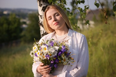Photo of Woman with bouquet of beautiful wildflowers outdoors on sunny day