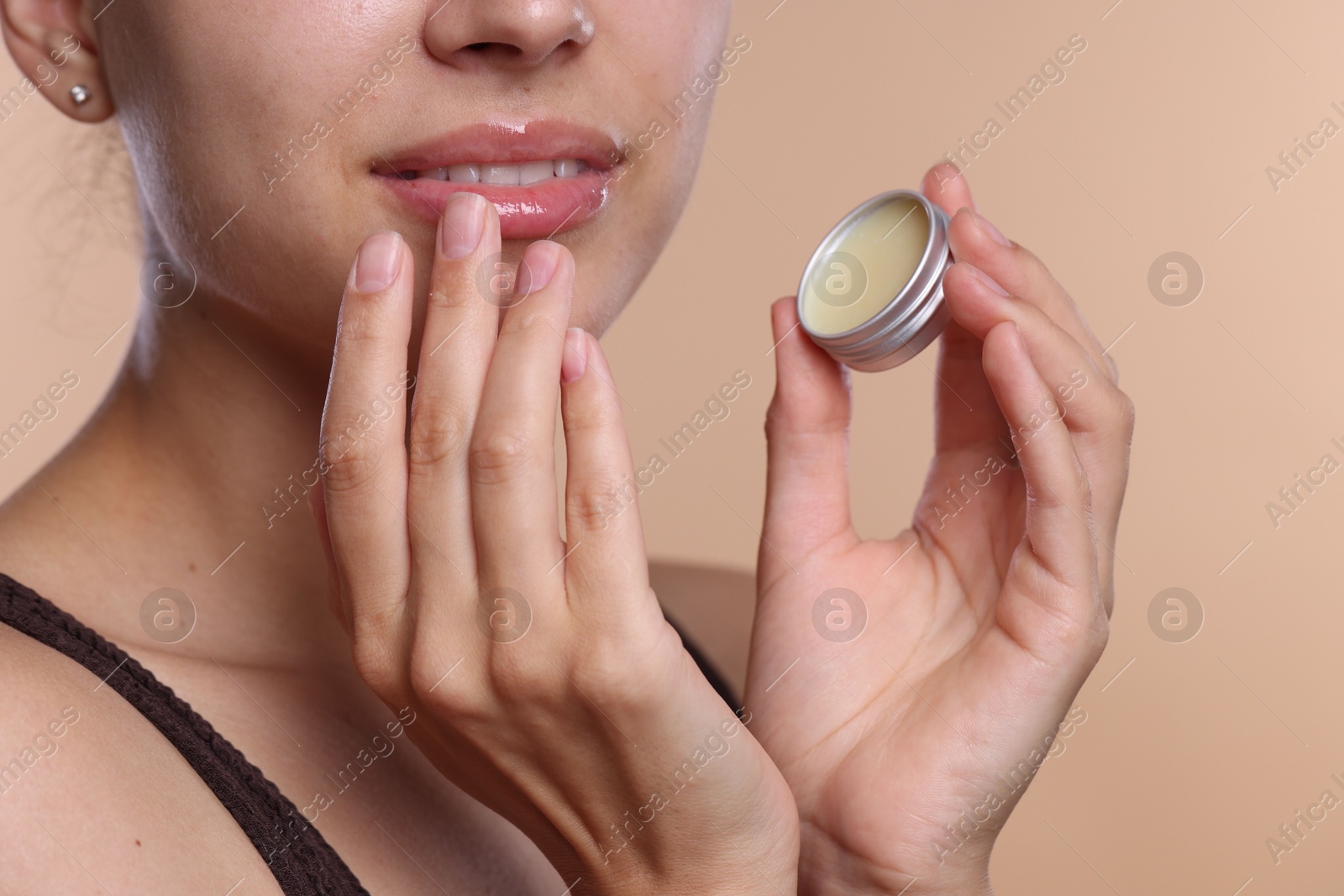 Young woman with lip balm on beige background, closeup Photo of Young woman with lip balm on beige background, closeup