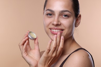 Photo of Young woman with lip balm on beige background