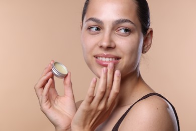 Photo of Young woman with lip balm on beige background