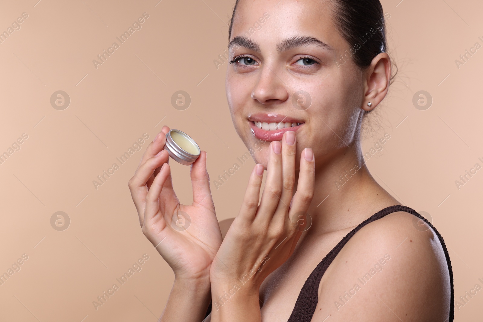 Photo of Young woman with lip balm on beige background