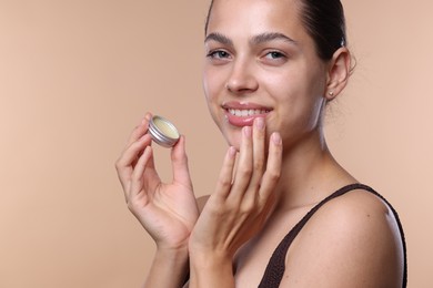 Photo of Young woman with lip balm on beige background