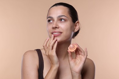 Photo of Young woman with lip balm on beige background