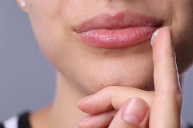 Photo of Young woman with lip balm on light grey background, closeup