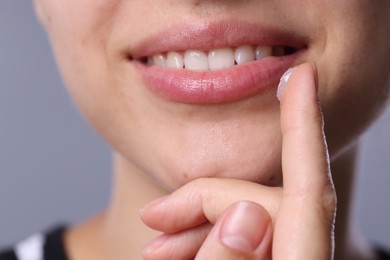 Photo of Young woman with lip balm on light grey background, closeup