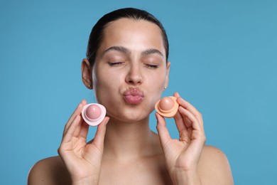 Photo of Young woman with lip balms on light blue background