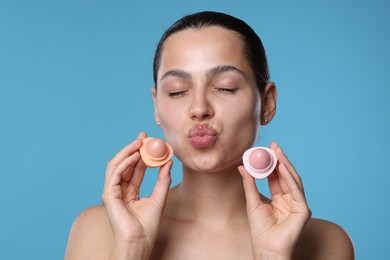 Photo of Young woman with lip balms on light blue background
