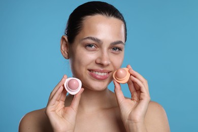 Photo of Young woman with lip balms on light blue background