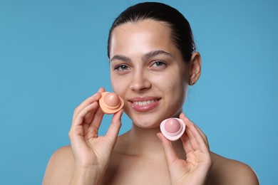 Photo of Young woman with lip balms on light blue background
