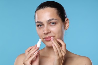 Photo of Young woman with lip balm on light blue background